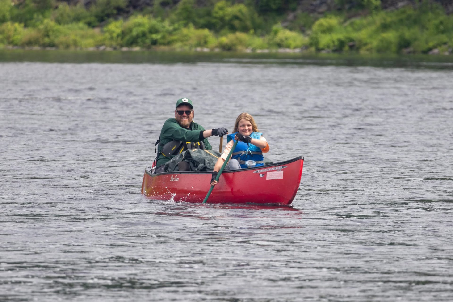 A man and young paddler in a red canoe on the river